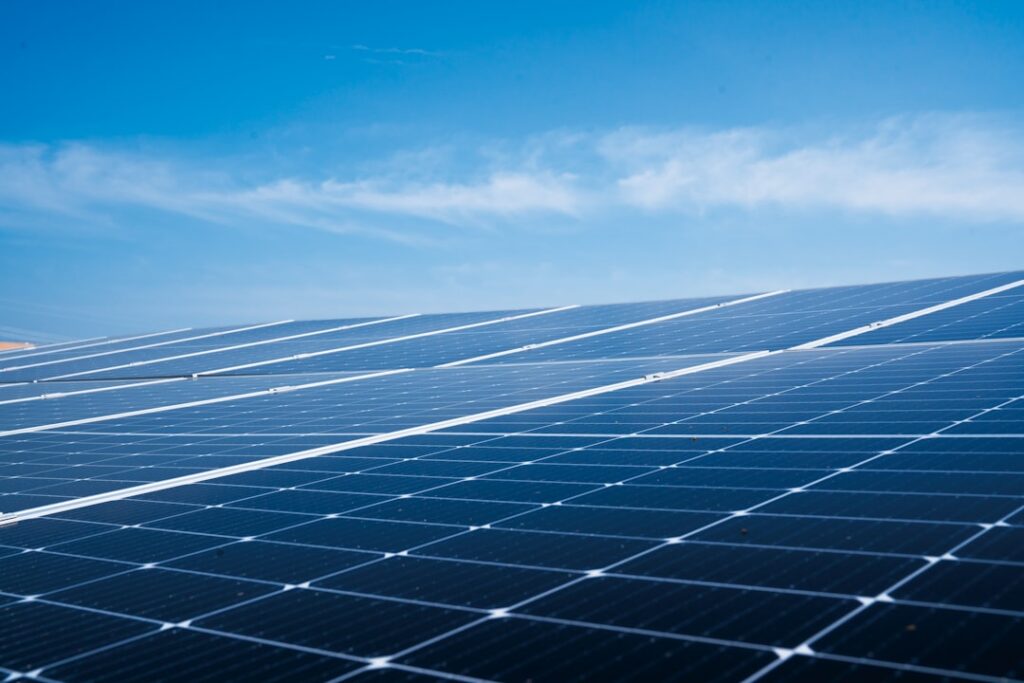 Solar panels mounted on a home rooftop under clear blue sky with leafy trees in the background.