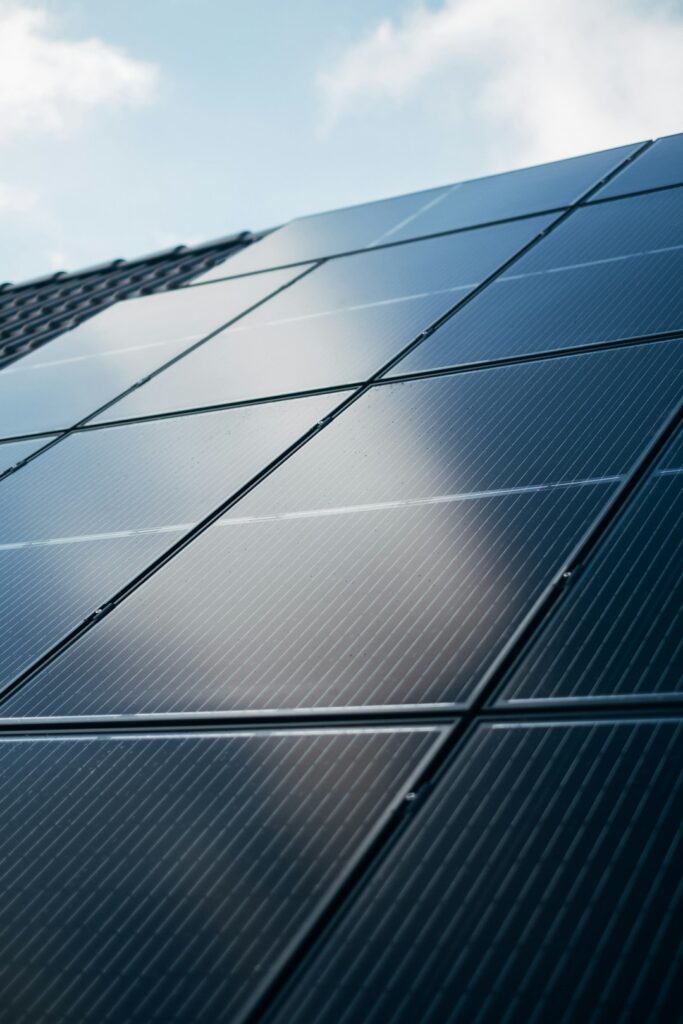 Technicians installing solar panels on a residential roof on a sunny day, with tools and safety equipment visible.