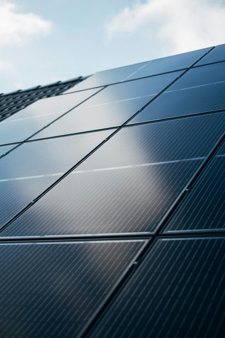 Technicians installing solar panels on a residential roof on a sunny day, with tools and safety equipment visible.