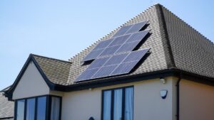 A family looking at solar panels installed on the roof of their house under a clear sky.